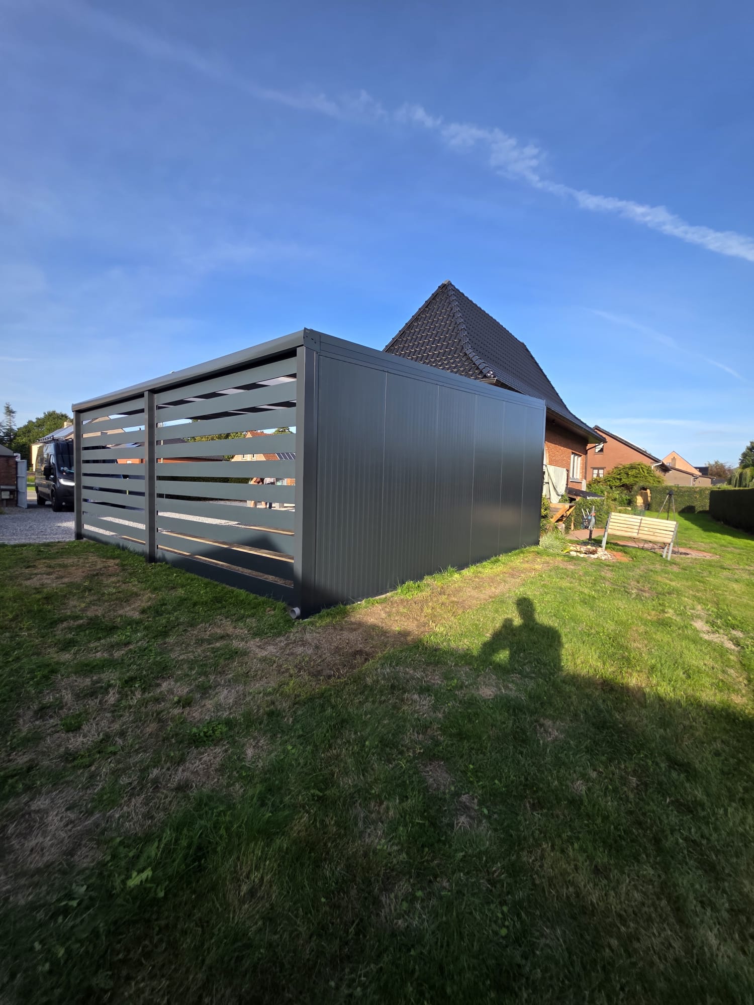 Overzicht van de vrijstaande antracietkleurige terrasoverkapping in Zonhoven vanaf de tuinzijde